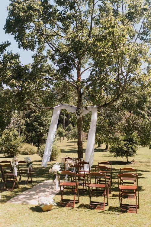 Free Peaceful outdoor wedding setup with chairs and decorations under a tree on a sunny day. Stock Photo