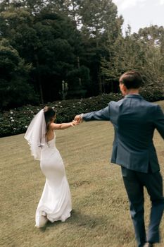 Bride and groom joyfully twirl in a lush garden setting, celebrating their special day.