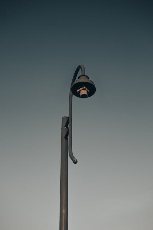 Free Low angle of modern high metal street lamp against gray sky at daytime Stock Photo