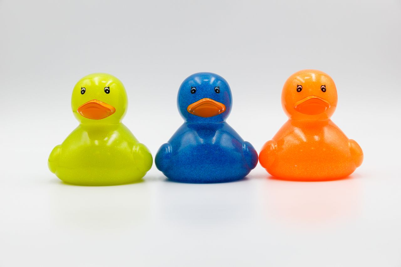 three colorful rubber ducks in green blue and orange on a white backgr