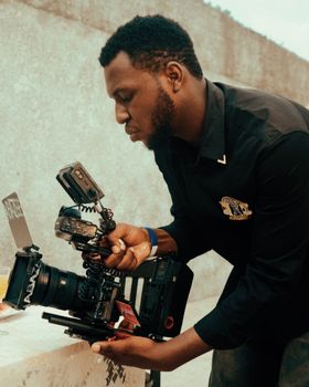 A focused videographer adjusts high-end camera equipment outdoors, preparing for a shoot.