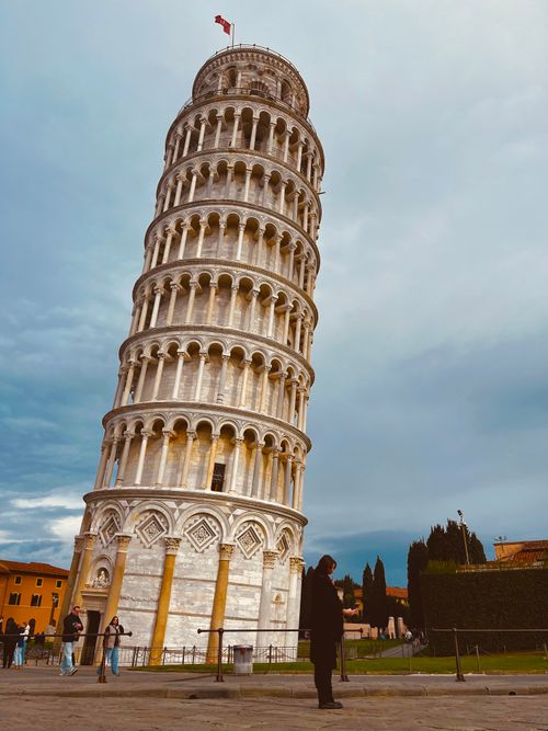 Free Capture of the iconic Leaning Tower of Pisa against a cloudy sky, showcasing its unique tilt. Stock Photo