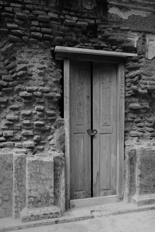 Free A rustic wooden door set in a weathered stone wall, showcasing historic architecture. Stock Photo