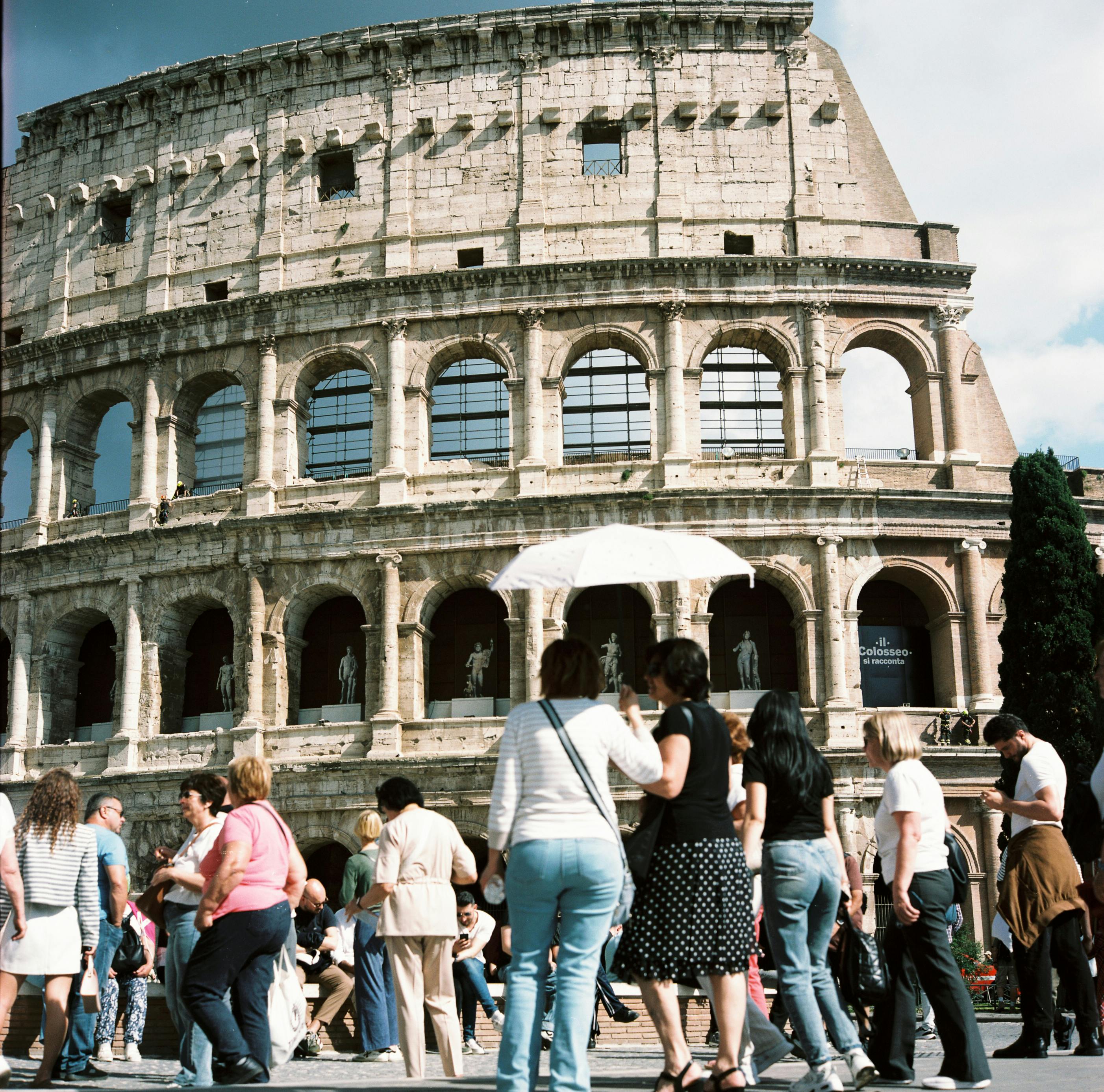 Visitors gather at the iconic Colosseum in Rome, capturing its historic charm on a sunny day.