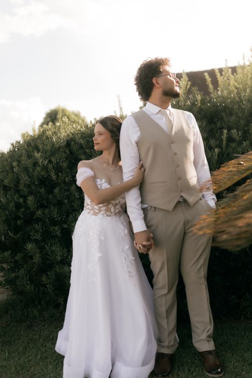 Free Charming outdoor wedding portrait of a couple in elegant attire, embracing in natural surroundings. Stock Photo