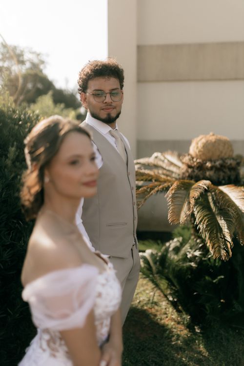 Free A stylish couple poses in a sunlit garden, capturing a timeless wedding moment. Stock Photo