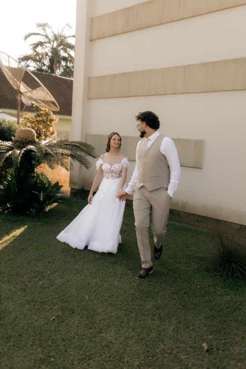 Free A joyful couple in wedding attire walking outdoors, captured in natural light. Stock Photo