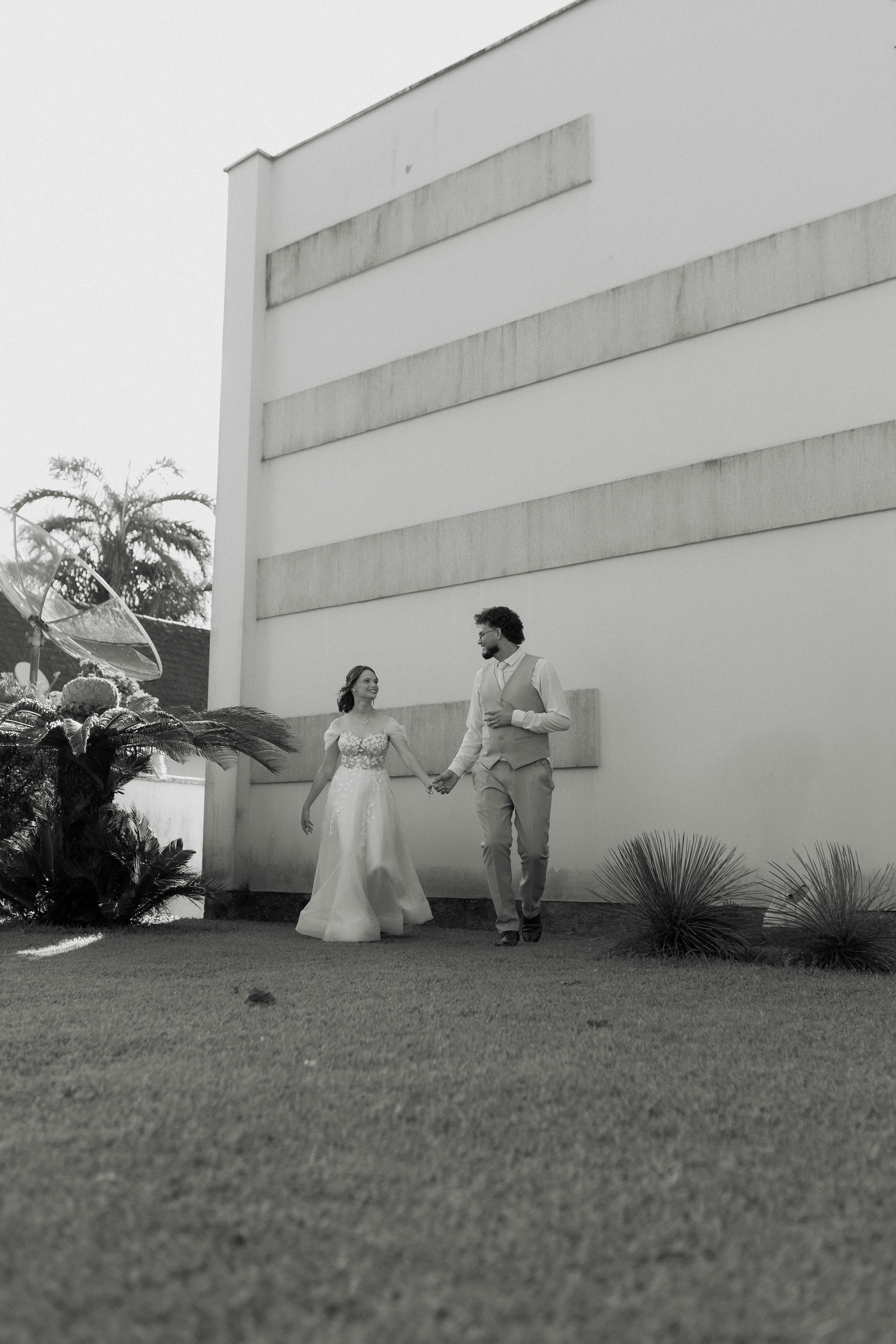 Black and white photo of a couple walking hand in hand outdoors, exuding elegance.