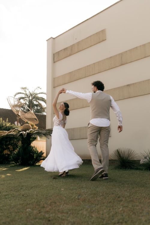 Free Happy bride and groom dancing on a sunny day outdoors, showcasing fresh joy and elegance. Stock Photo