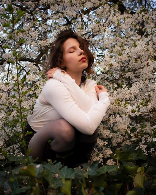 Free A serene portrait of a young woman amidst lush spring blossoms, depicting tranquility and natural beauty. Stock Photo