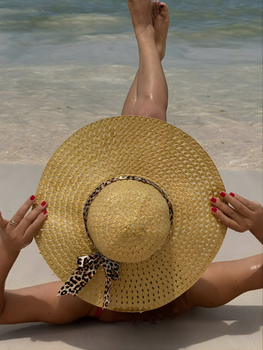 Woman in straw hat enjoys a sunny day at the beach, embracing summer relaxation.
