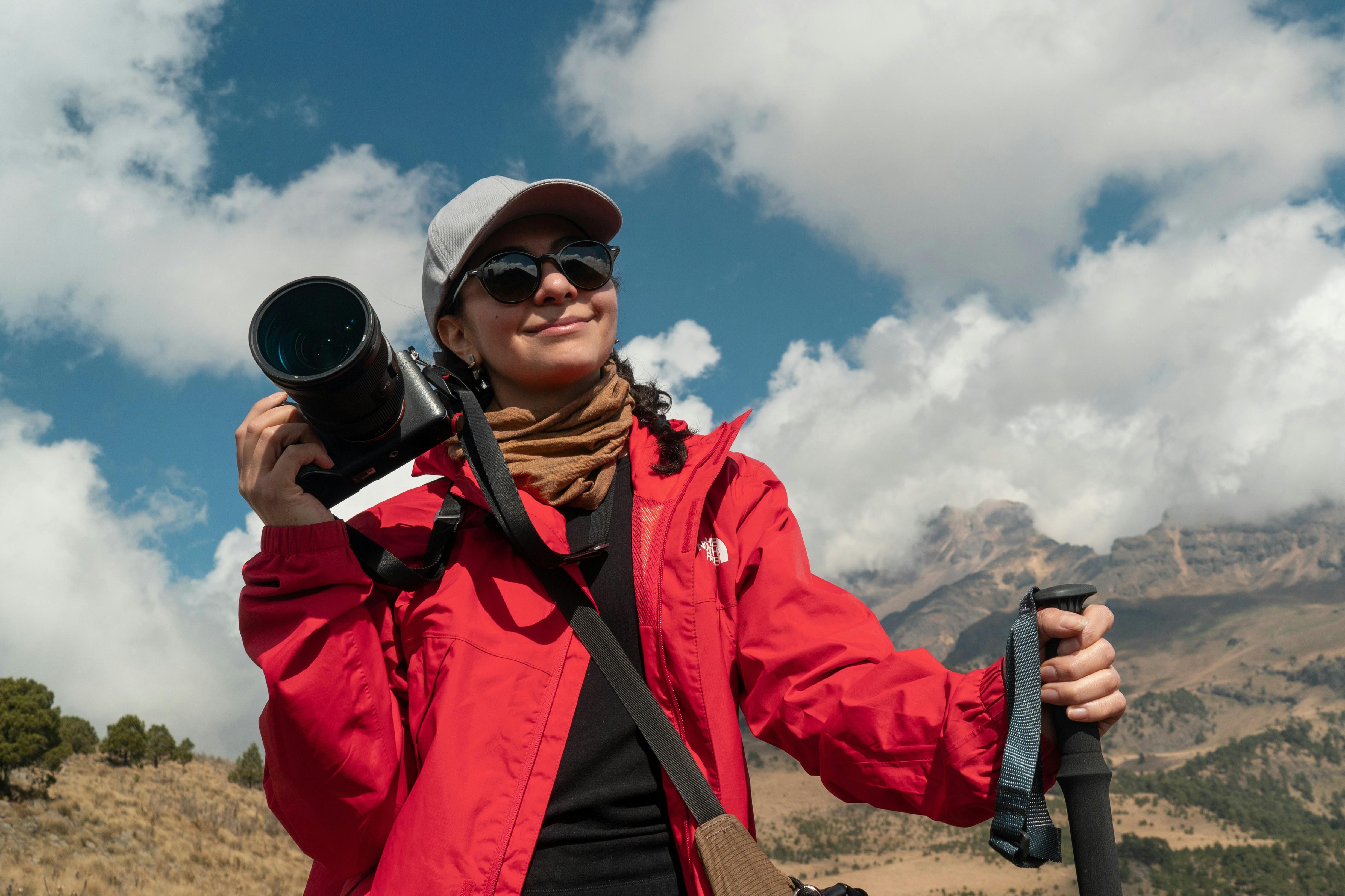 Photographer enjoying a mountain hike with camera gear, bright sunny day.