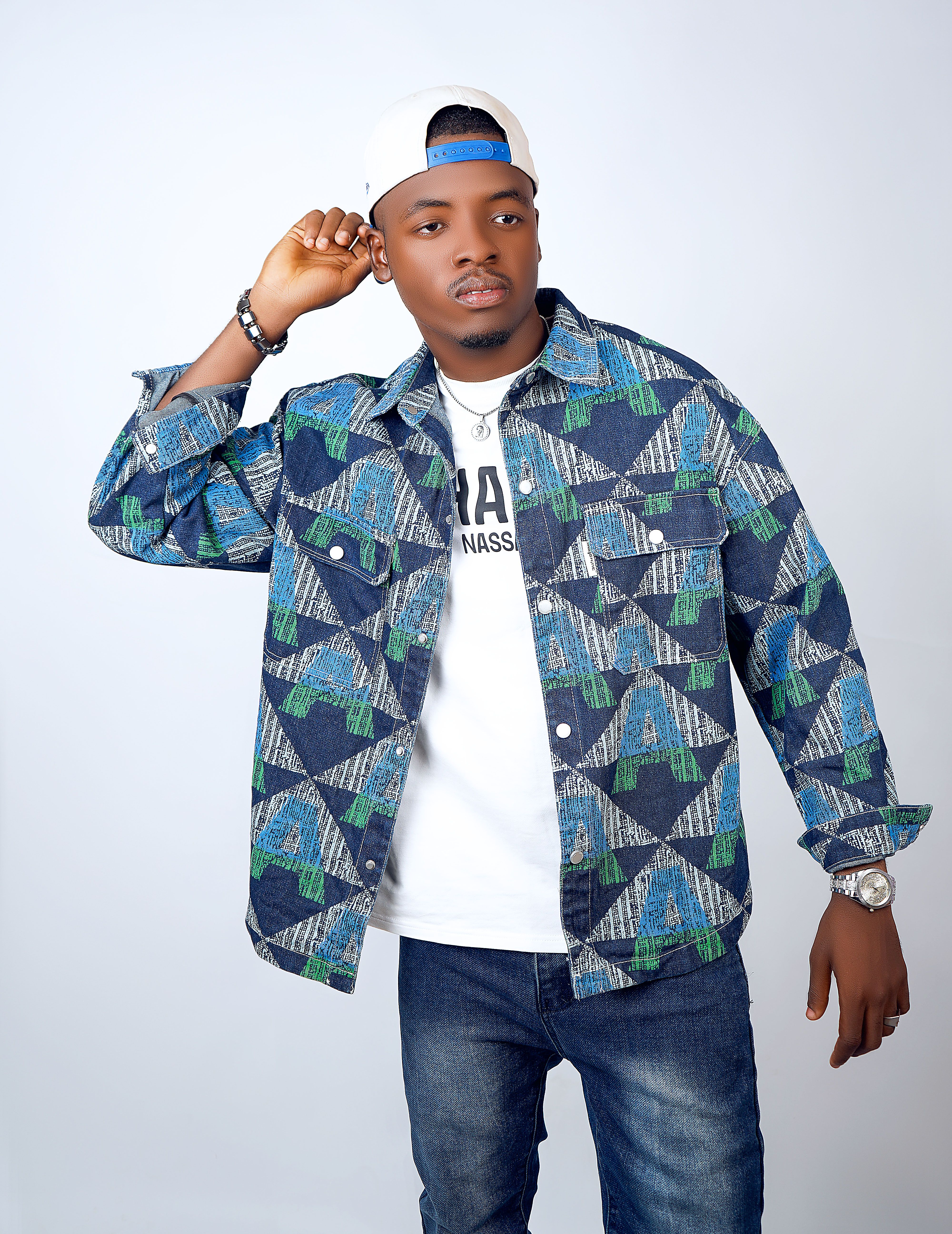 Stylish young adult male wearing a denim shirt and baseball cap in a casual pose.
