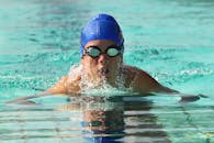 专注的游泳运动员在室外游泳池练习泳姿，展现运动决心