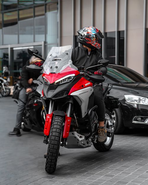 Free A motorcyclist in urban attire on a red motorcycle, in a city setting. Stock Photo