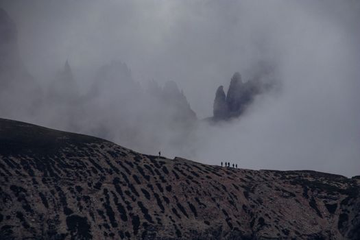 A group of hikers silhouetted against a misty mountain background.