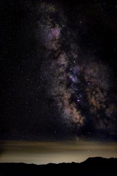 A breathtaking shot of the Milky Way galaxy against a starry night sky over a mountain range.