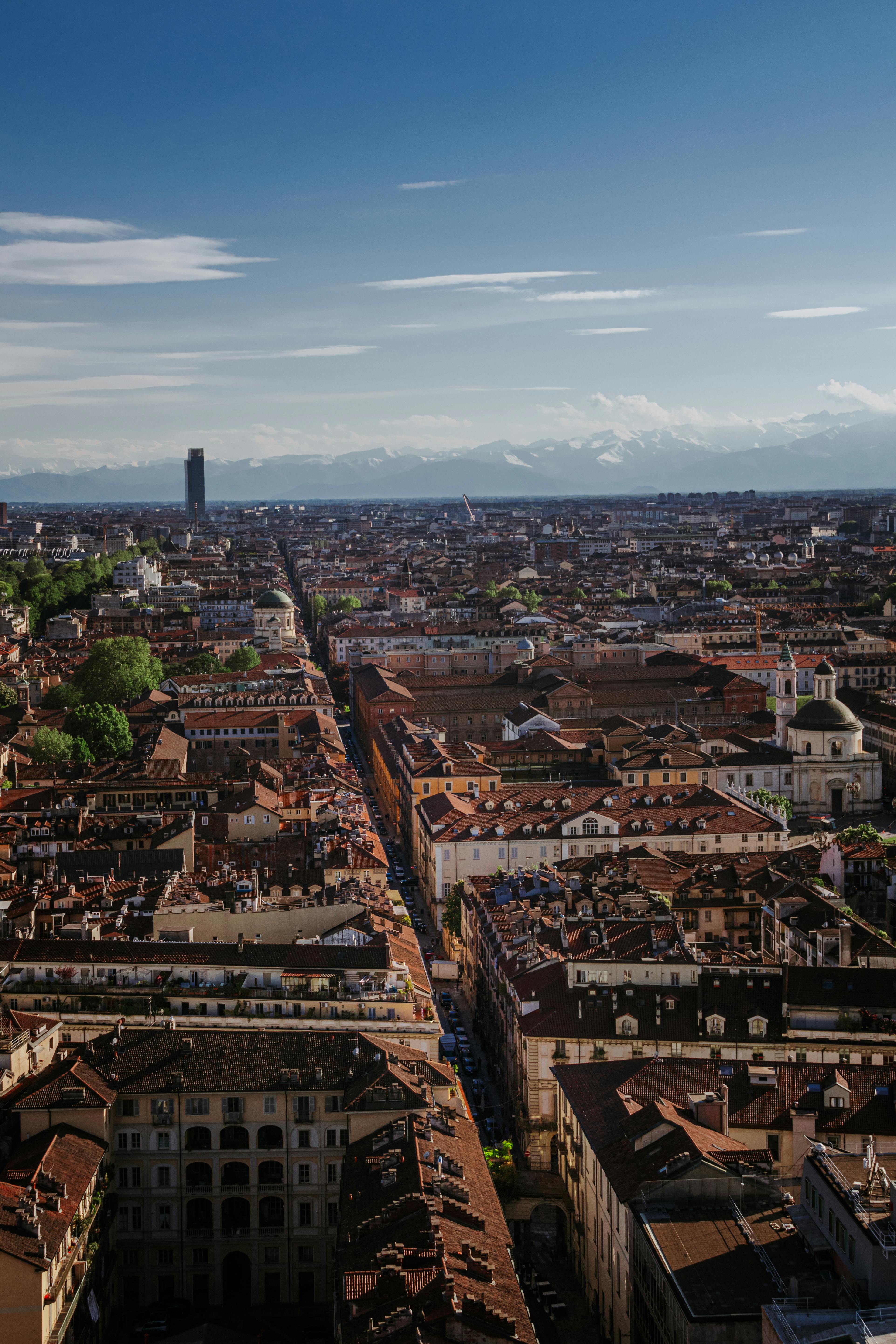Stunning aerial view of Turin, Italy with cityscape and distant mountains under a vibrant sky.