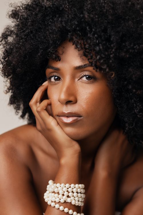 Free Striking portrait of a woman with natural curls and pearl bracelets showcasing elegance. Stock Photo
