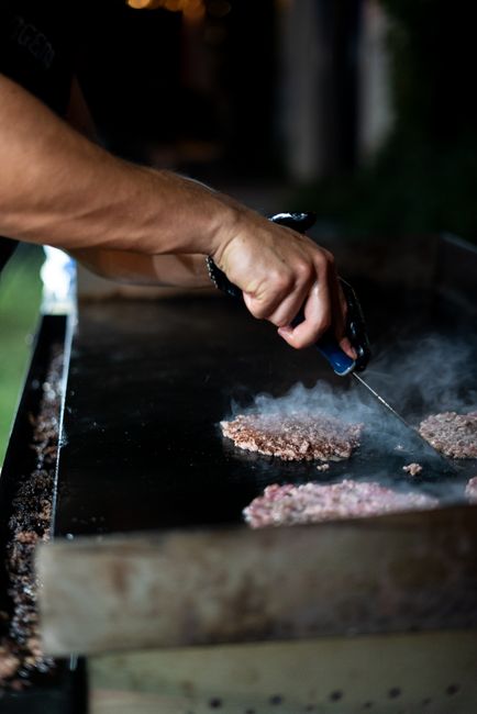 Two thin smash burger patties with deep brown lacy crust and melted American cheese stacked on a toasted bun on a flat-top griddle.