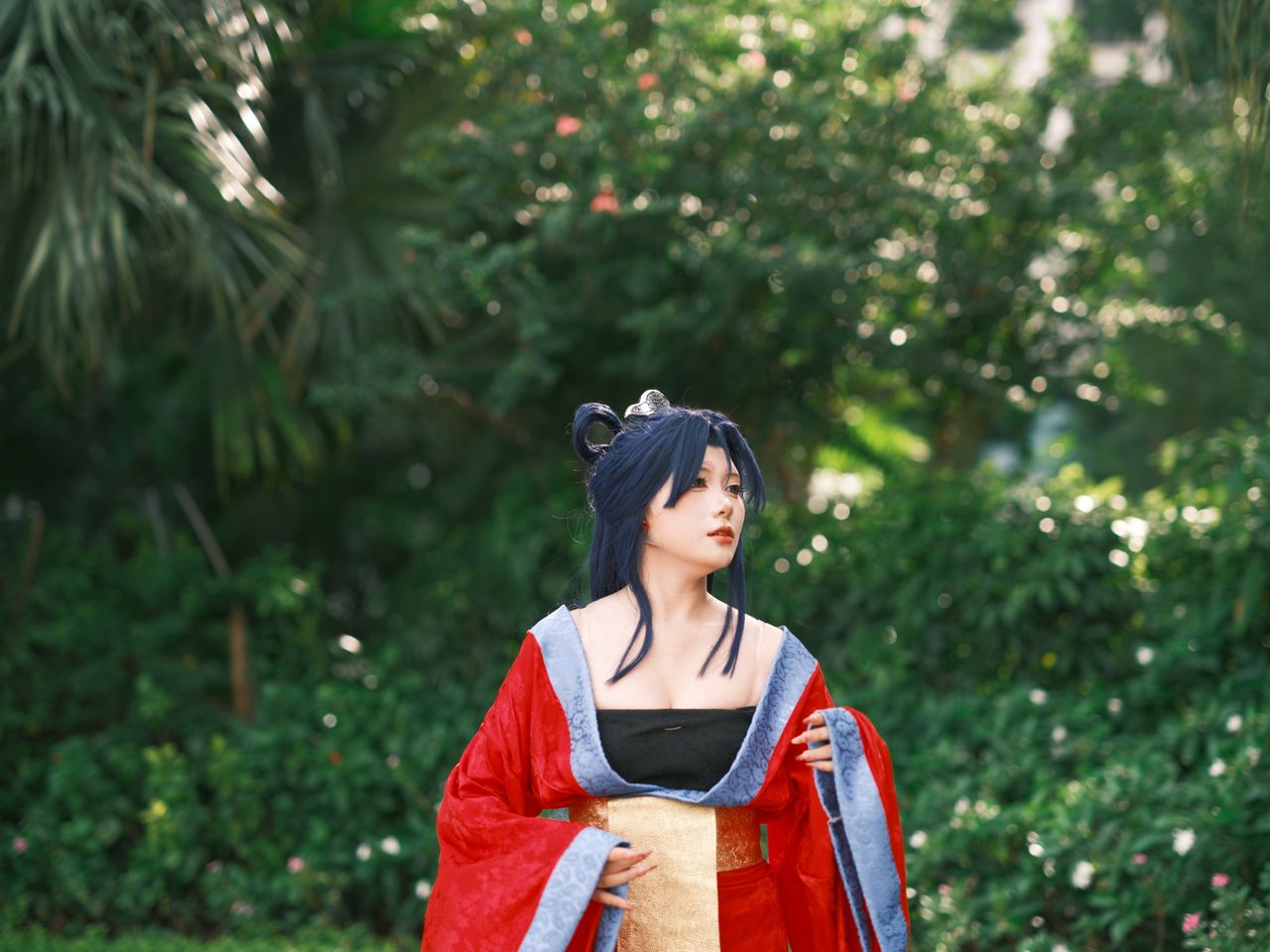 a woman in a vibrant traditional costume posing in a lush green outdoo