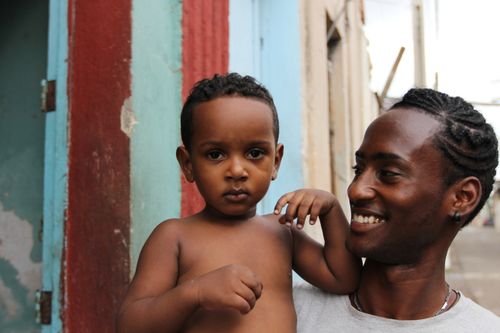 Free Smiling father holding child in colorful Havana street, Cuba. Stock Photo