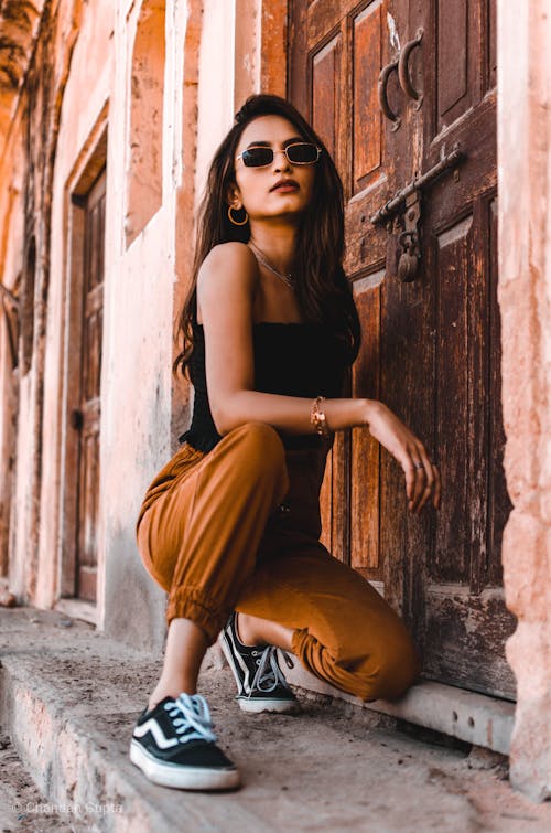 Woman Wearing Shades While Kneeling Near Wooden Door