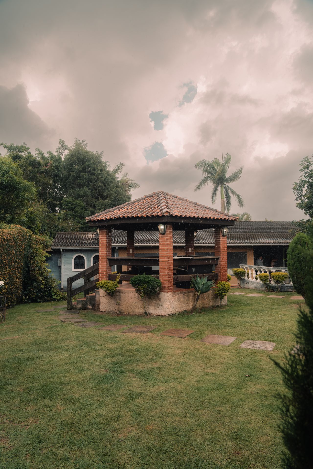 Brick gazebo with a clay tile roof in a landscaped garden
