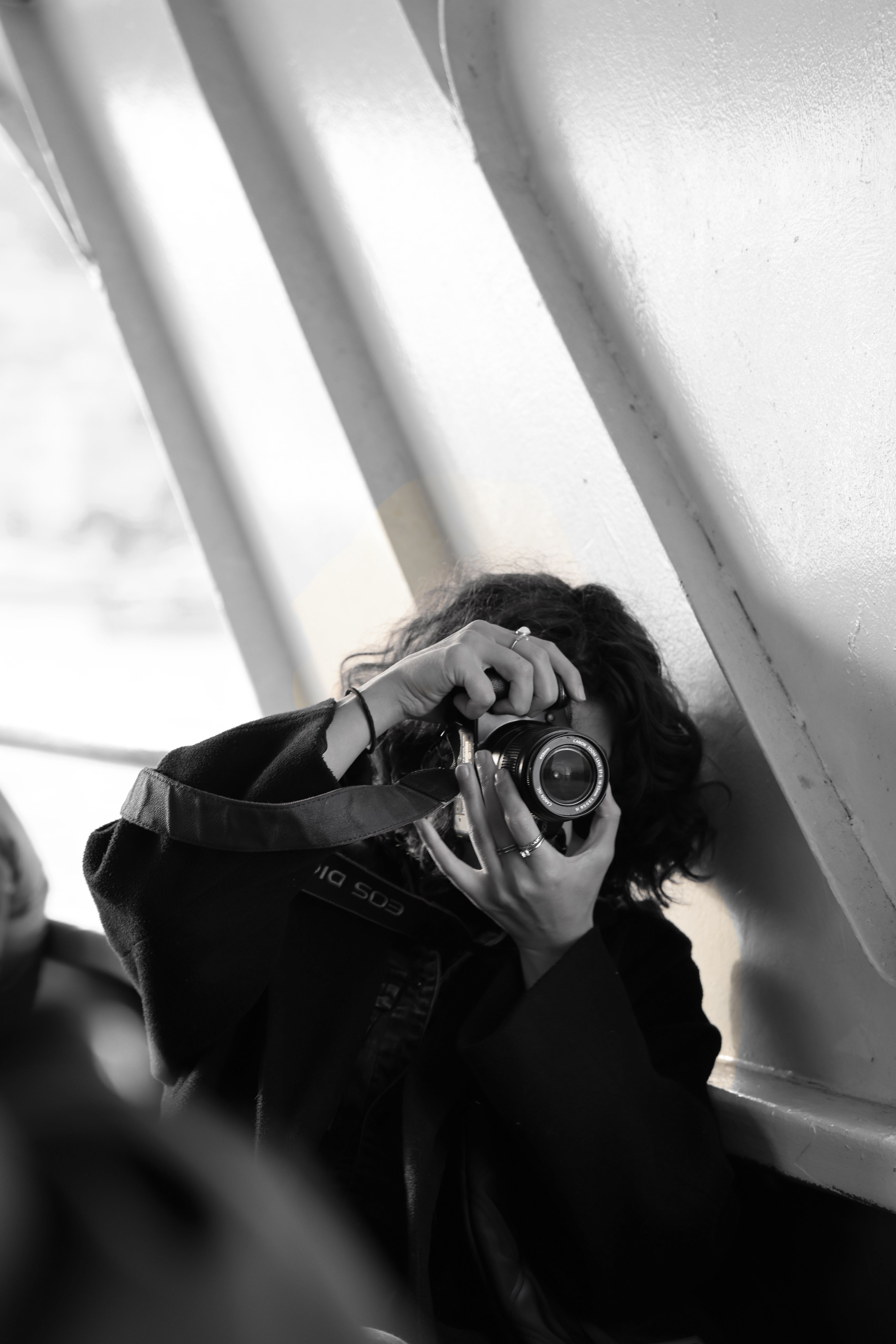 Black and white shot of a photographer capturing a candid moment indoors.