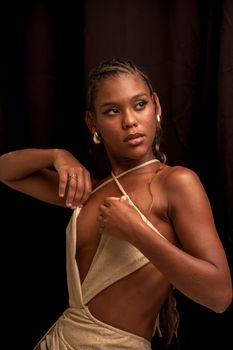 A woman in a stylish dress poses against a dark backdrop, exuding elegance and confidence.