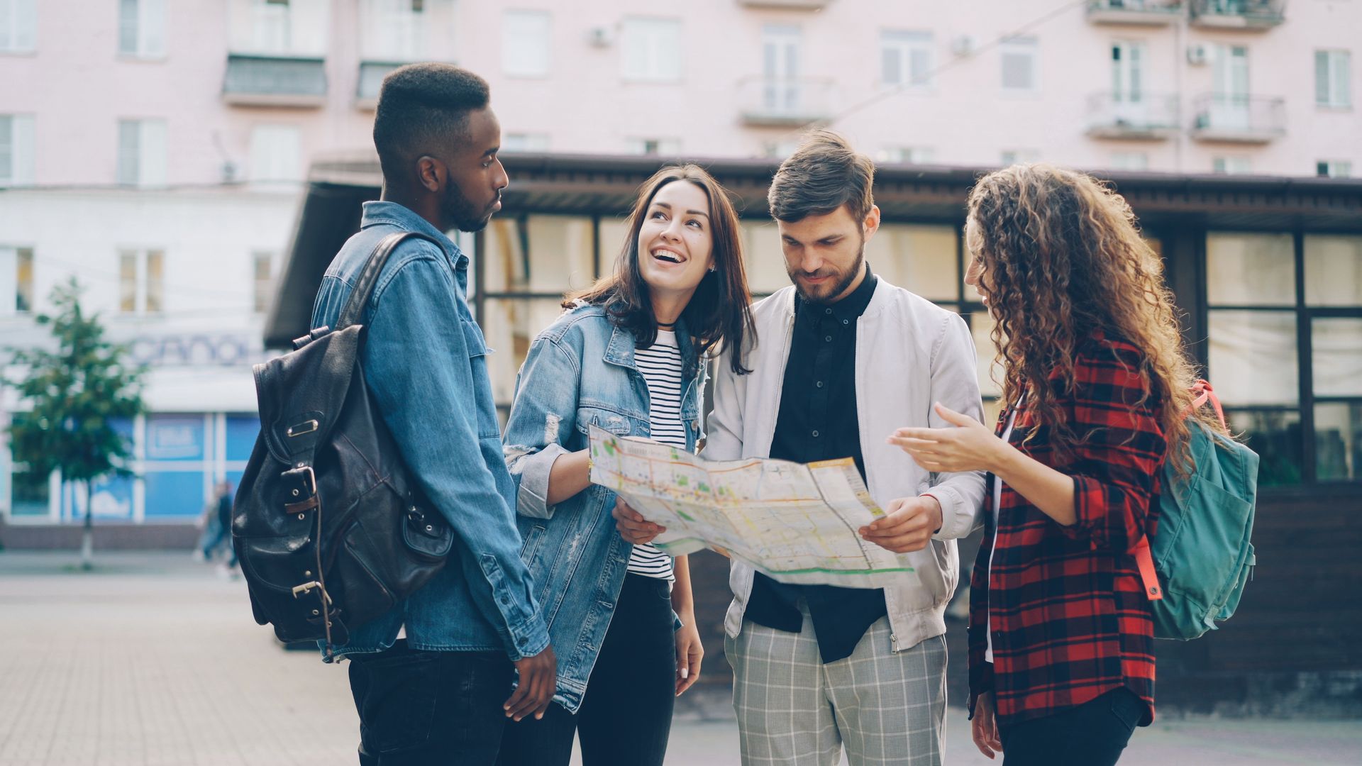 Grupo de amigos internacionais conferindo um mapa em uma rua da cidade