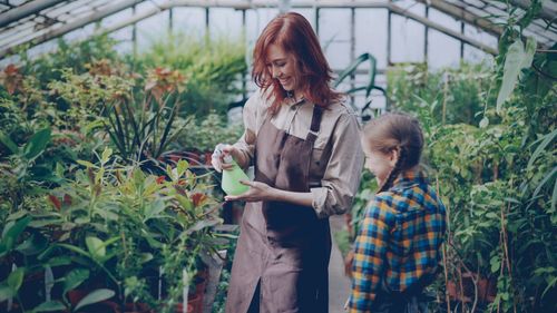 Free A woman and child enjoying gardening together in a greenhouse setting. Stock Photo