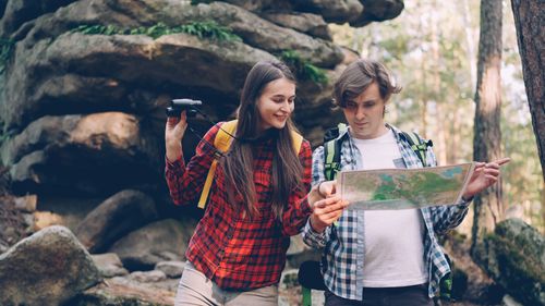 Free Couple exploring nature with map and binoculars in a forest setting. Stock Photo