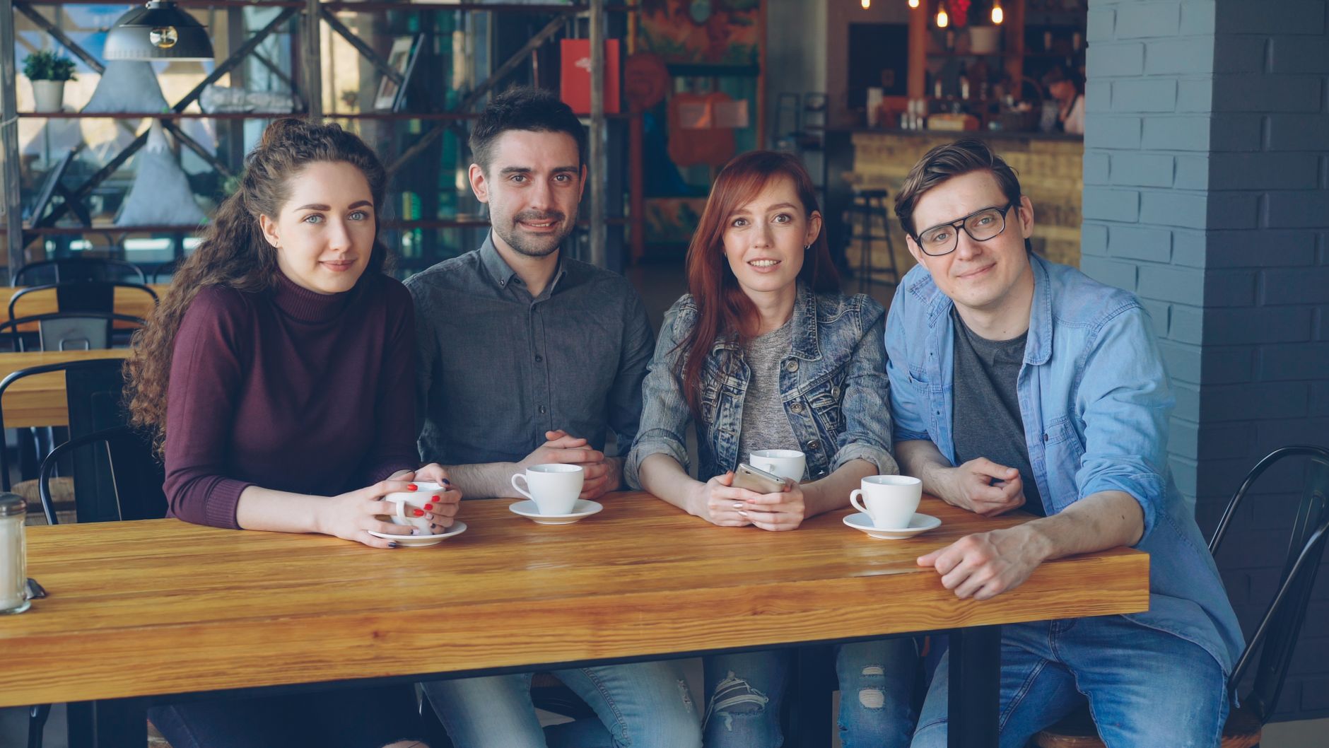 Twee taalmaatjes voeren een gesprek aan een tafeltje met koffie