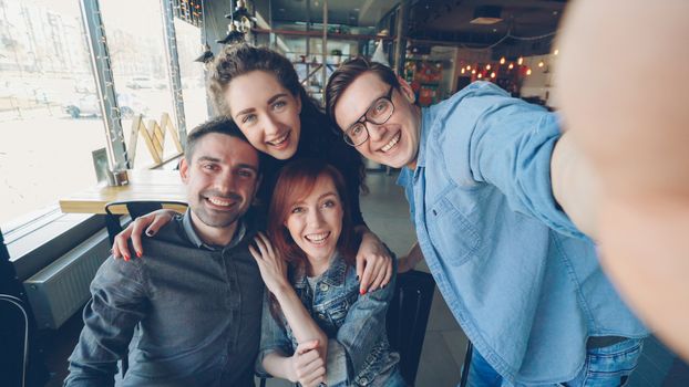 Happy group of friends taking a selfie together in a cozy cafe setting.