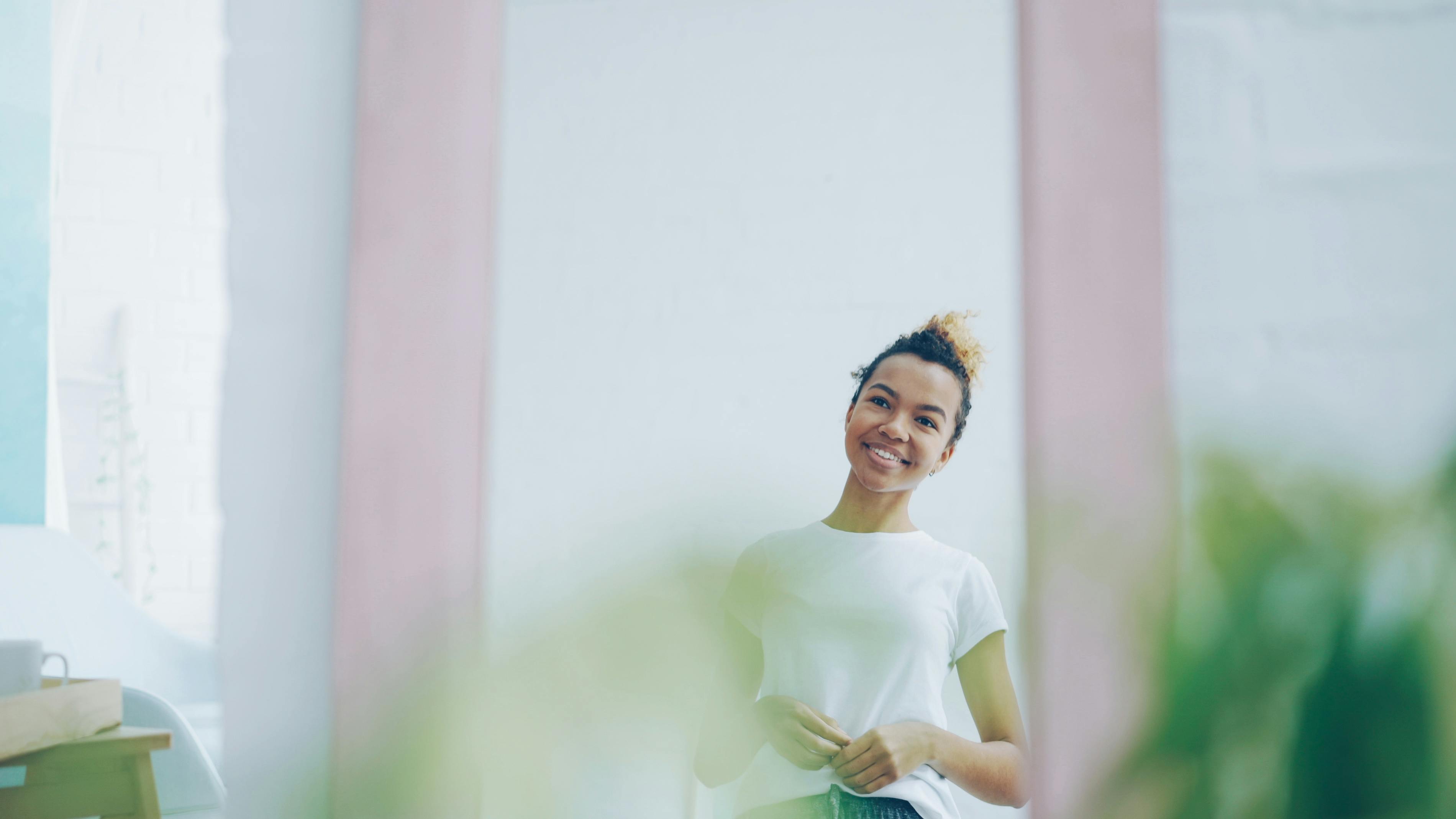happy woman in a simple bright minimalist room with plants
