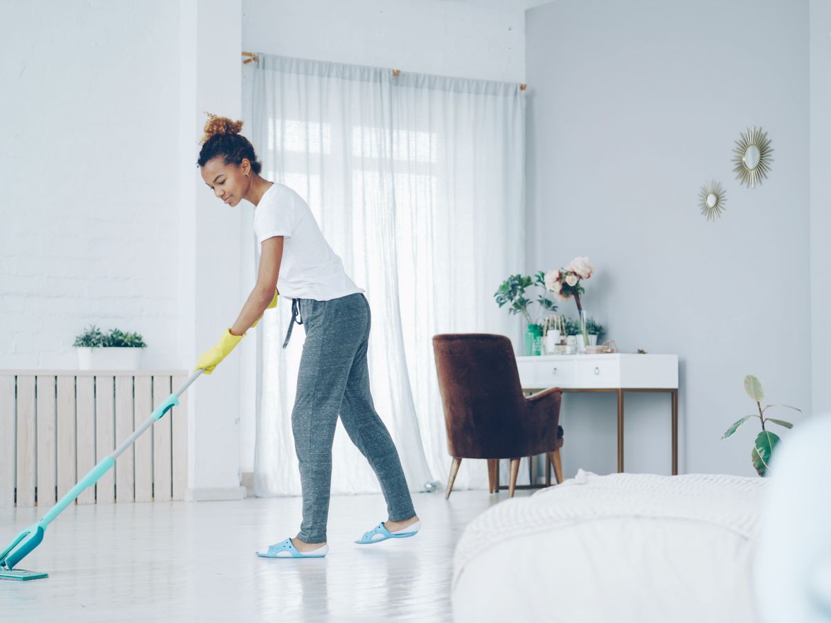 Cleaner mopping a bright, tidy living room