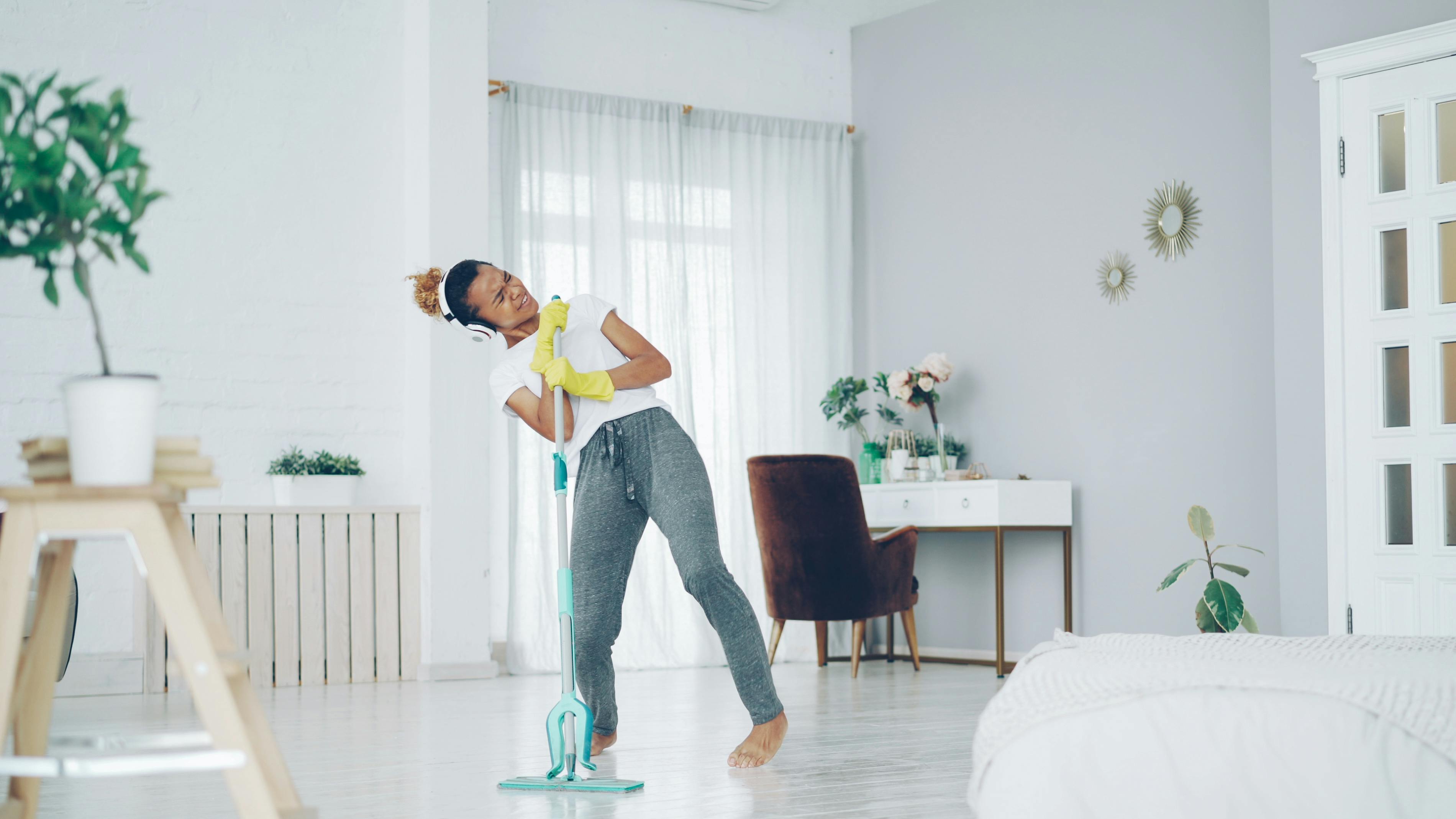 joyful woman dancing while cleaning in a minimalist home
