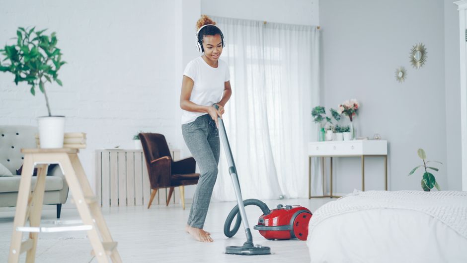 Top Robot Mop and Vacuum Combos for Hard Floors (2025 Review) A woman in a cozy room uses a vacuum cleaner while enjoying music on headphones.