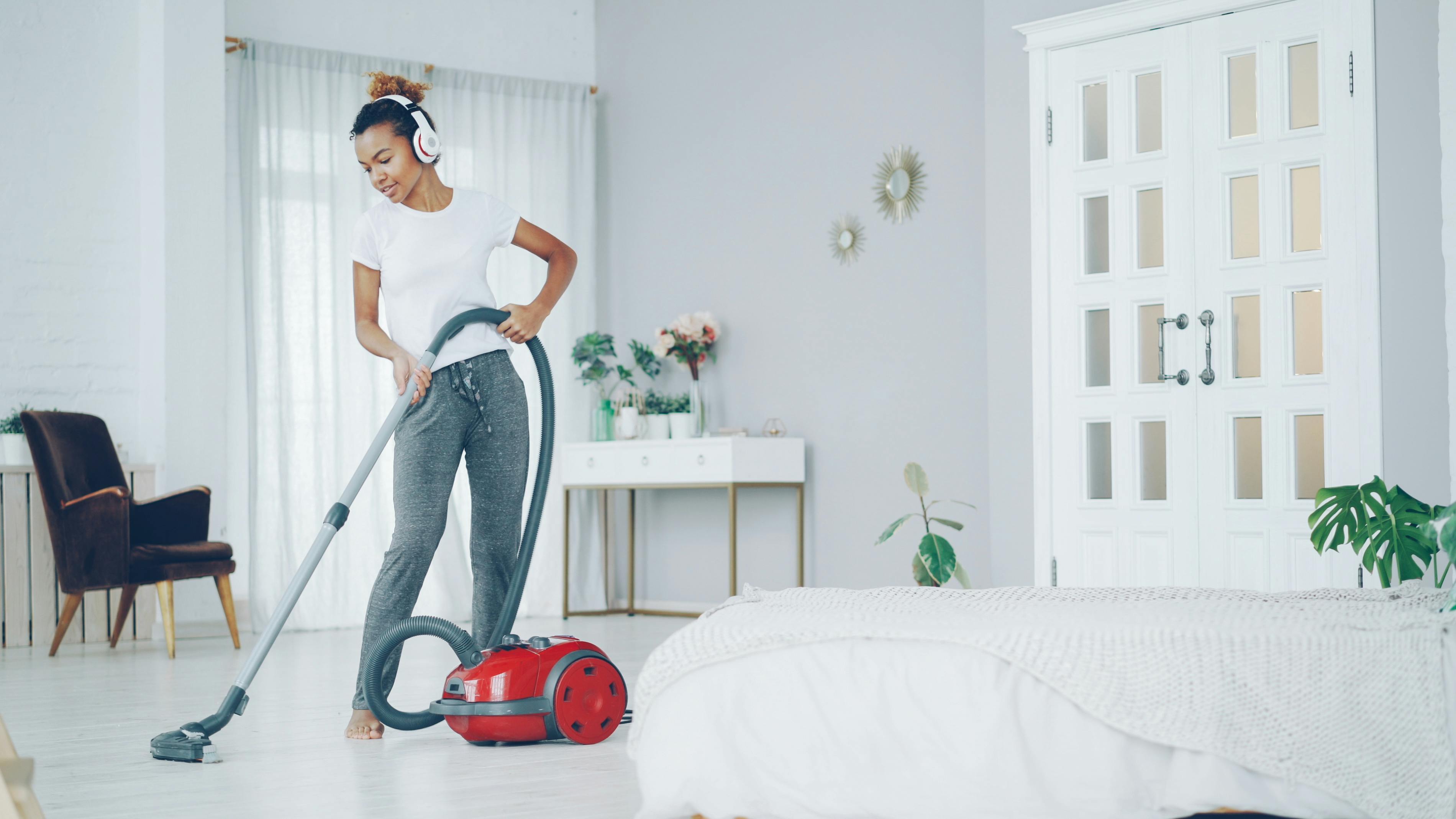 Woman vacuuming in a stylish modern room while listening to music, enjoying cleaning.