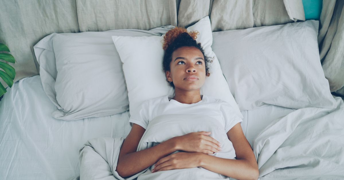woman lying in bed doing breathing technique