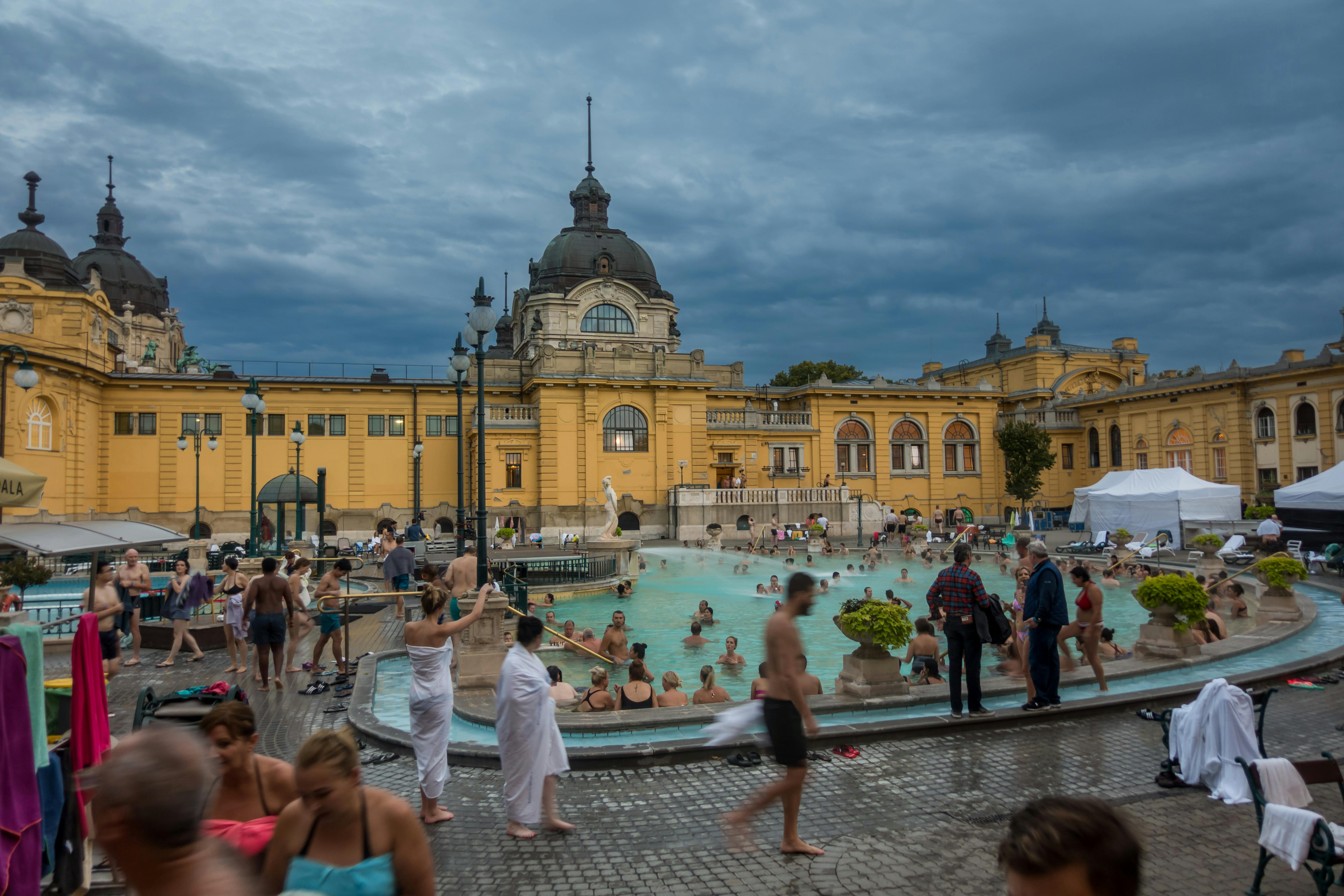 People enjoying Széchenyi Thermal Bath in Budapest, featuring historic architecture.