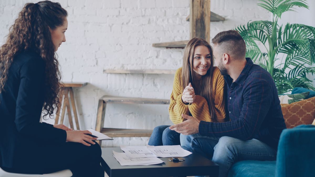 Smiling couple discussing real estate plans with advisor in modern, cozy setting