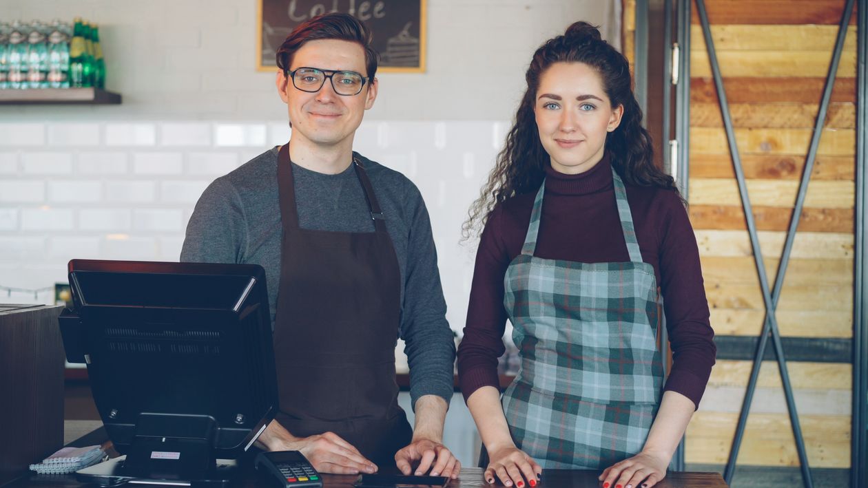 Smiling cafe employees behind the counter ready to serve customers
