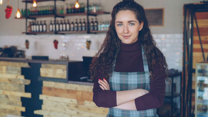 A cafe owner with arms crossed in her cozy coffee shop