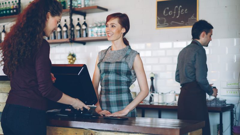 Staff serving a customer in a busy coffee shop &mdash; photo by Vitaly Gariev on Pexels