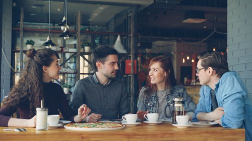 Free A group of adults having coffee and pizza at an indoor cafe setting. Stock Photo