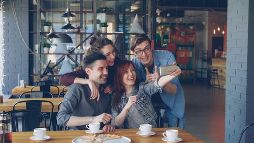 Free A joyful group of friends capturing a selfie together at a cozy café table. Stock Photo