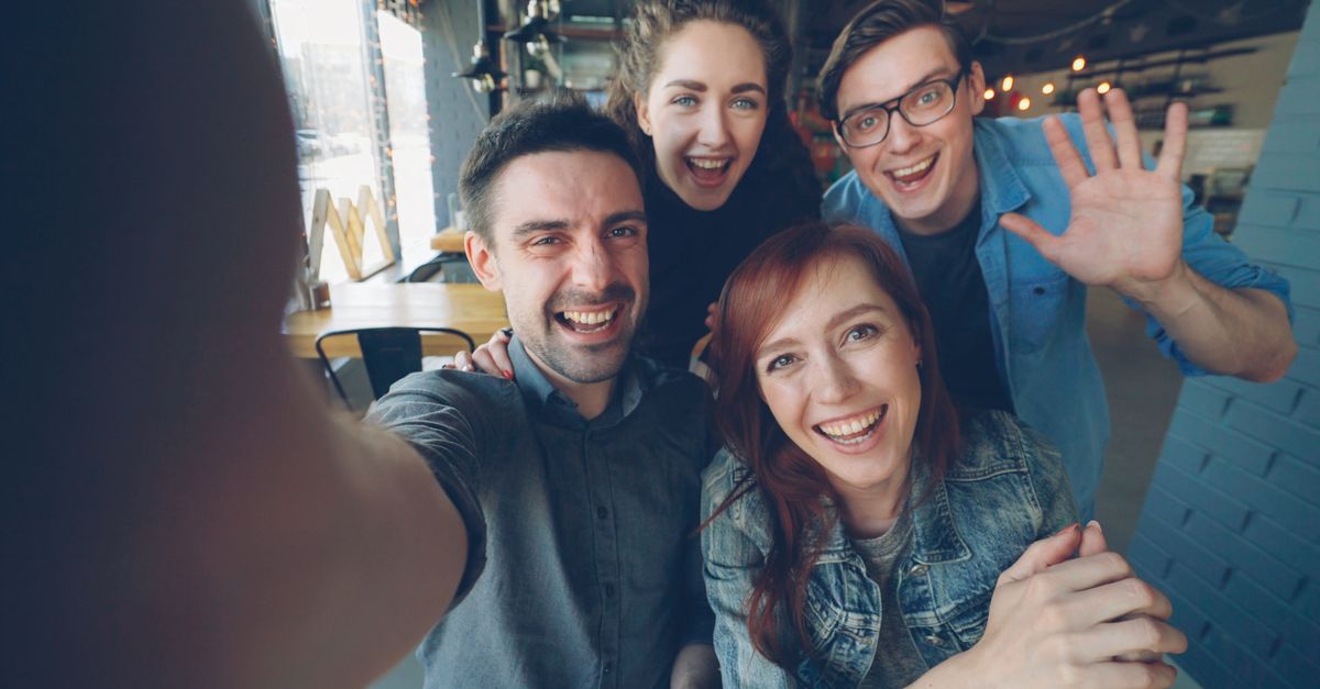 small group of people laughing together in a cozy coffee shop, natural light