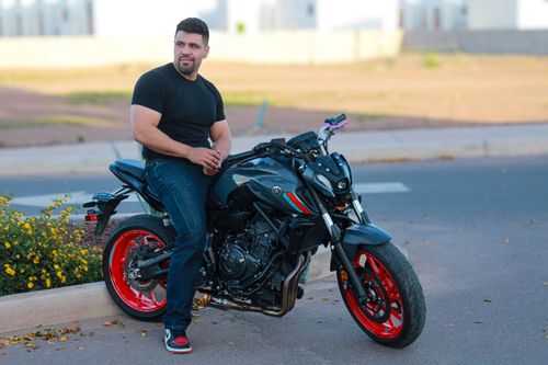 Free A man sitting on a stylish motorcycle by the roadside enjoying a sunny day. Stock Photo